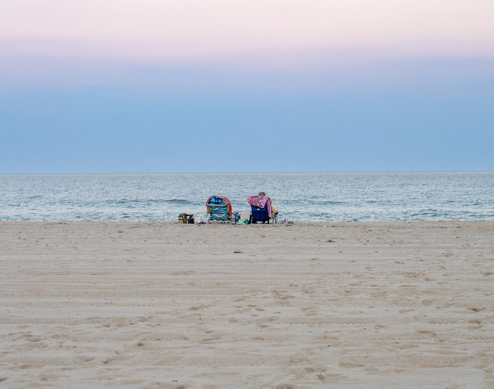 chairs on a beach with the ocean in the background